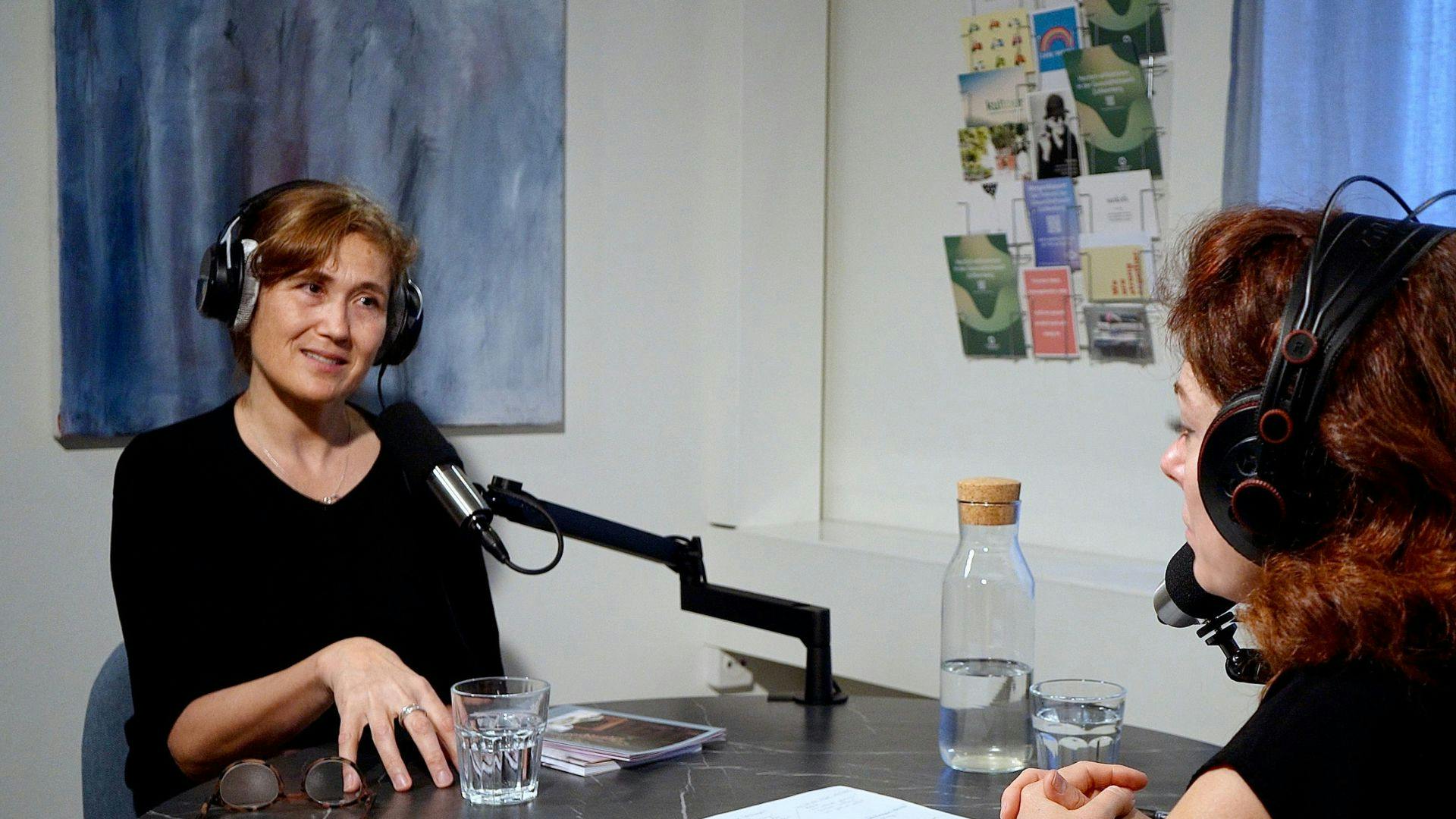 Frau mit Kopfhörern sitzt bei einem Podcast-Interview in einem Studio.